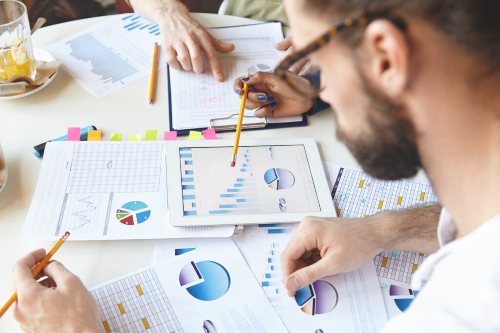 Group of professionals analyzing data on charts and documents in a meeting.