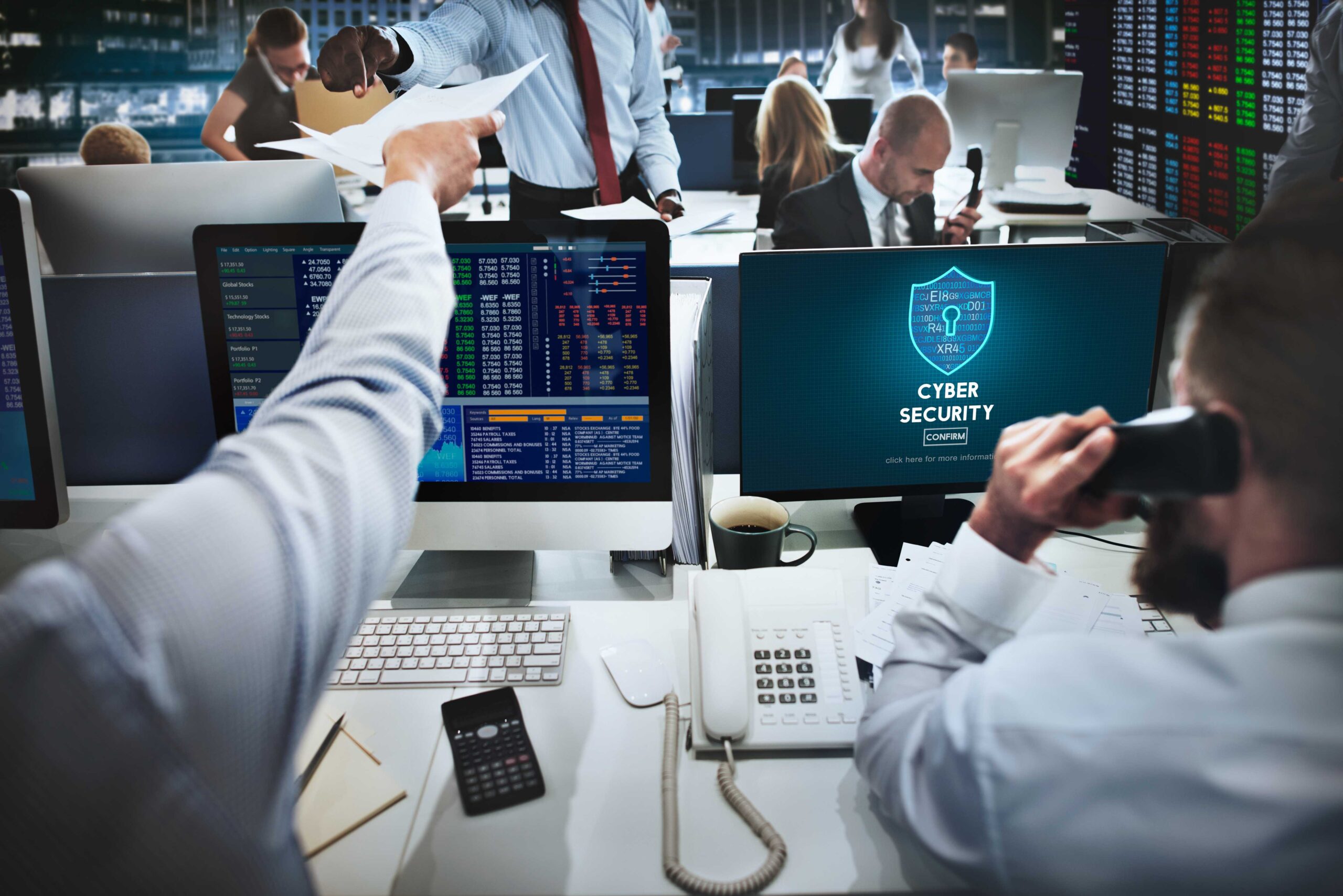 Group of professionals working at desks with computer screens in modern office setting