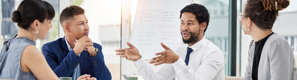 A diverse group of individuals engaged in a lively conversation while seated around a table, consulting providers strategize ways to navigate challenges and seize opportunities in today's dynamic business landscape.