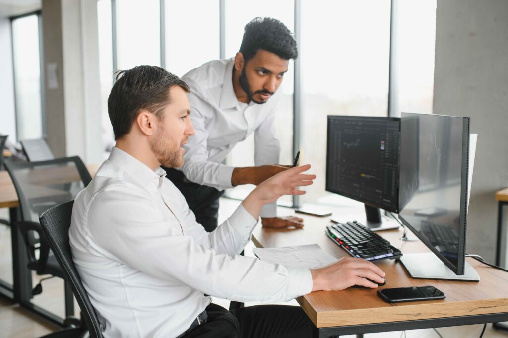 Two men collaborating on a computer in a modern office setting