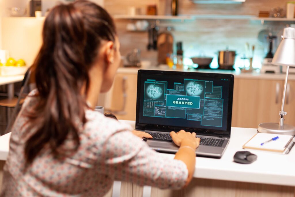 A woman sitting at a table with a laptop, working on her computer