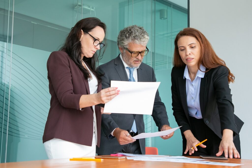 Three professionals discussing documents at a table