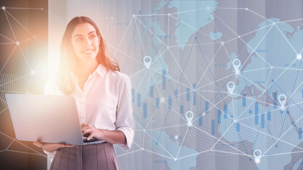 A woman holding a laptop, looking at a world map on the screen, benefiting from proactive IT solutions