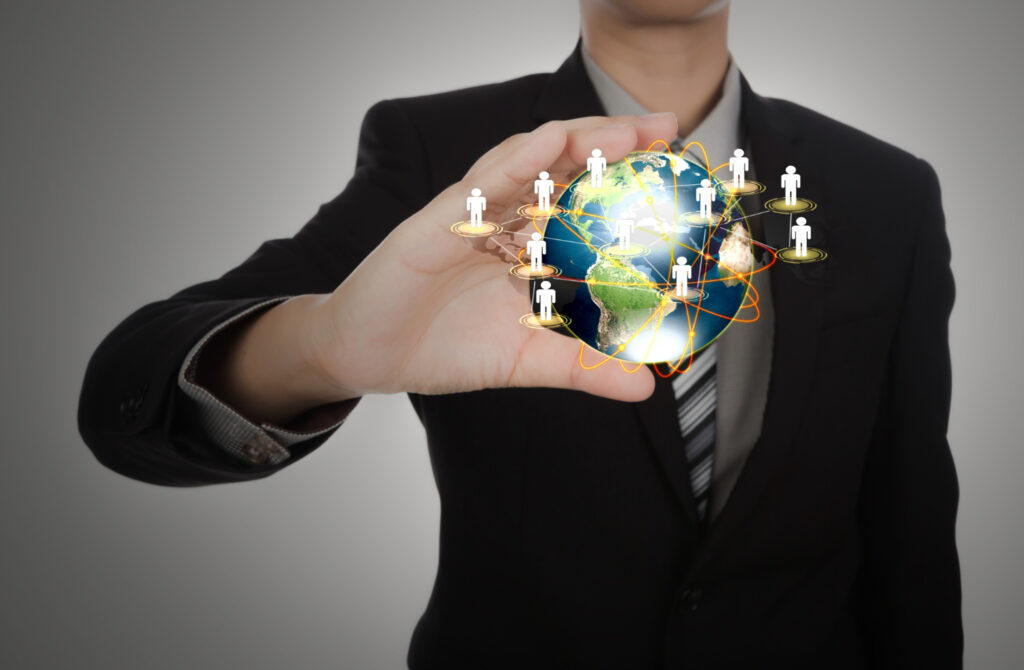 A businessman holding up a globe with miniature people on it