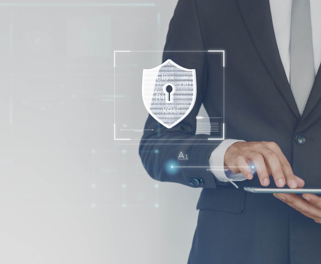 A businessman in a suit holding a tablet with a shield icon displayed on the screen