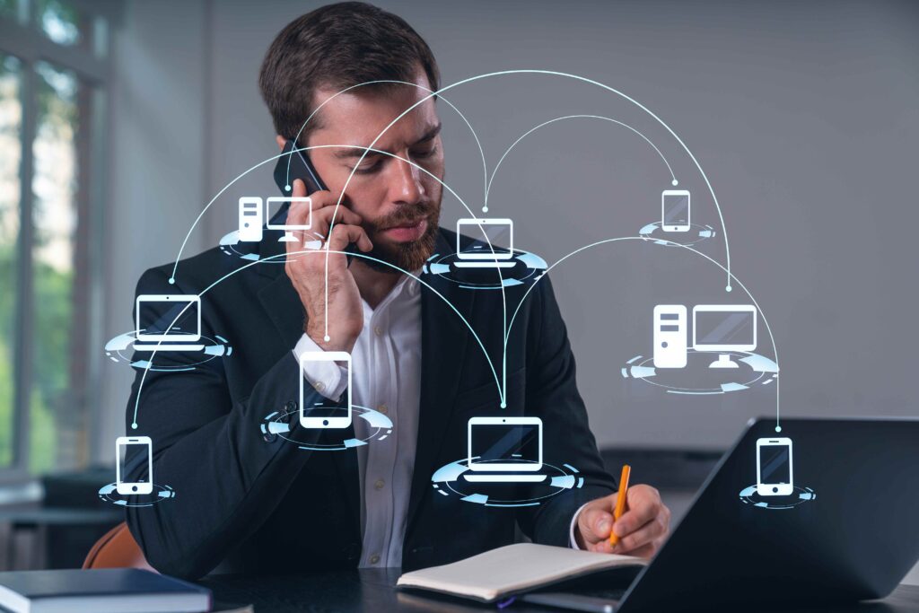 A man in a suit multitasking with a phone call and laptop usage