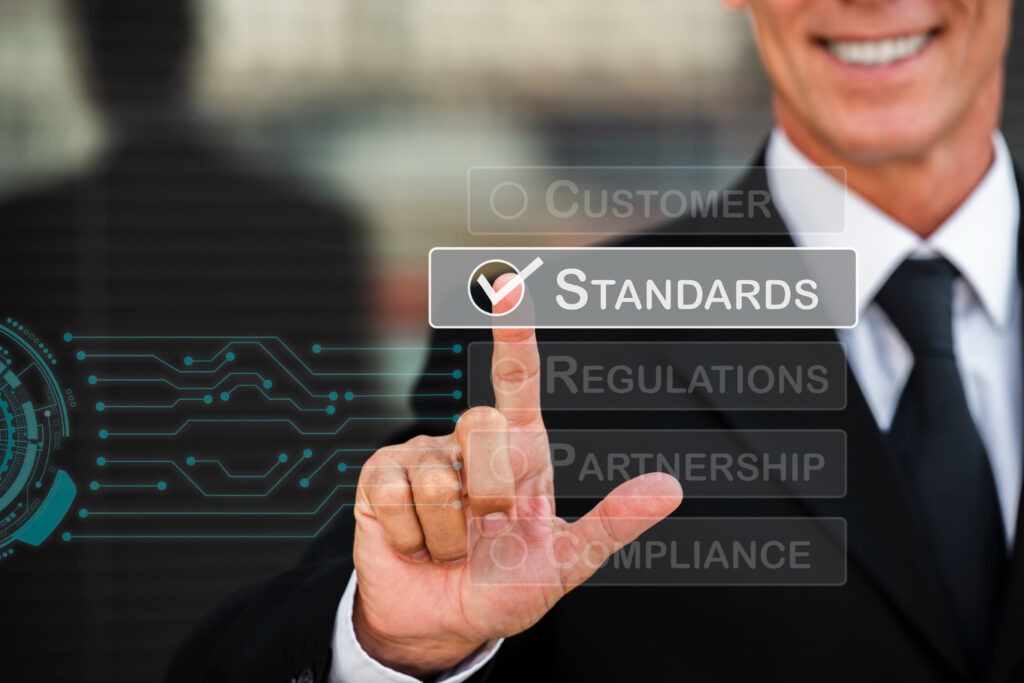 A man in a suit pressing a button labeled "standards" to ensure adherence to established guidelines.