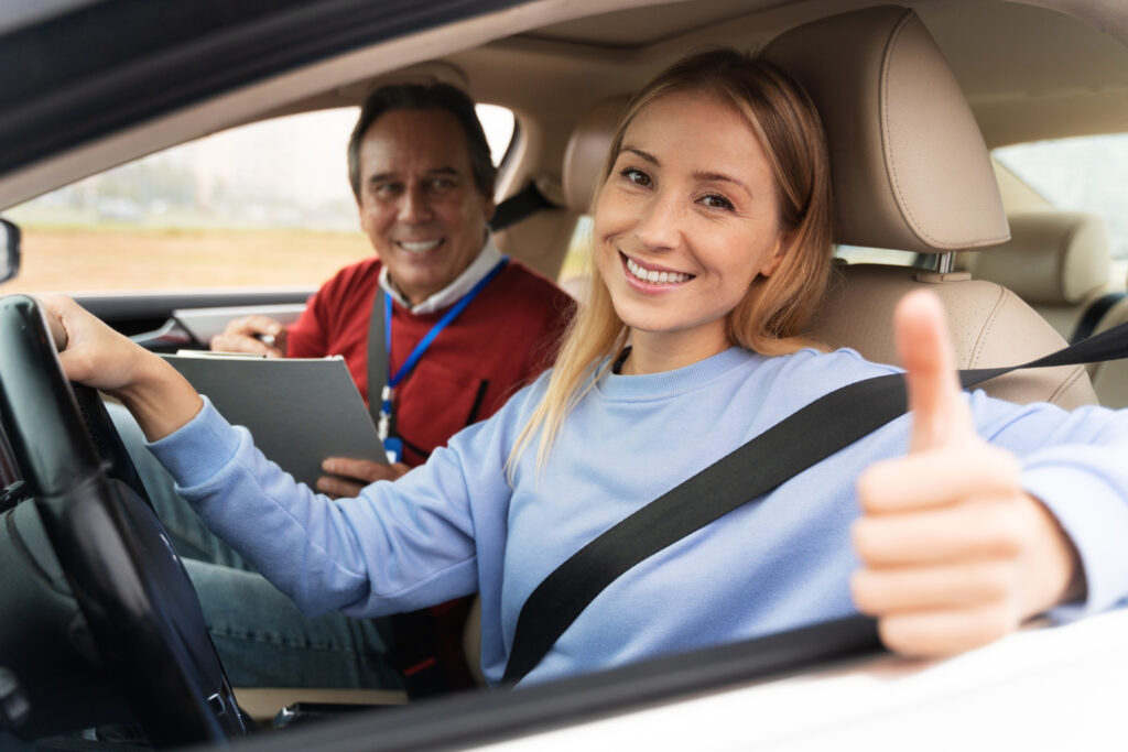 A woman and man in a car smiling and giving the thumbs up gesture