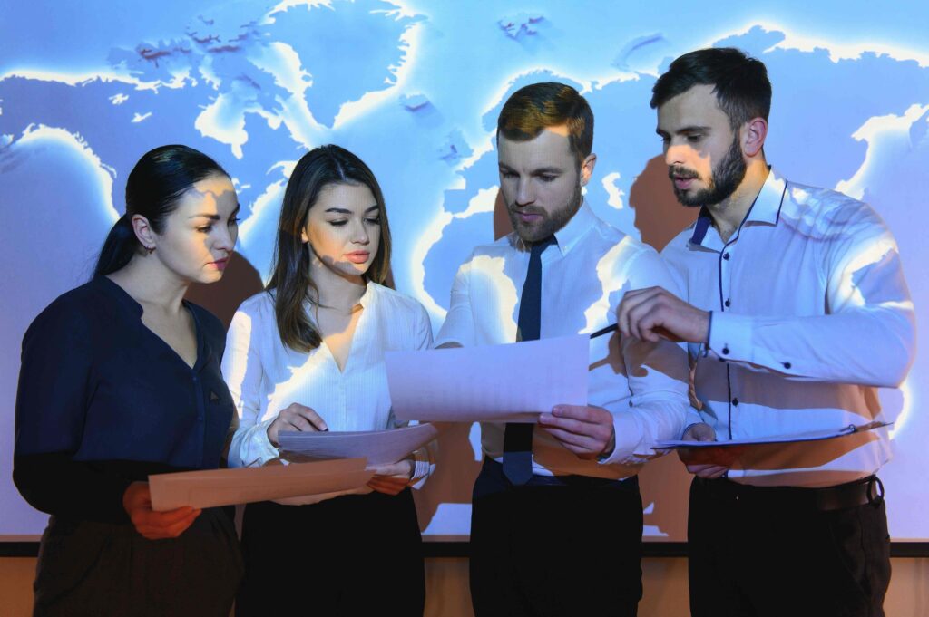 A group of business professionals standing in front of a map, discussing strategies and planning