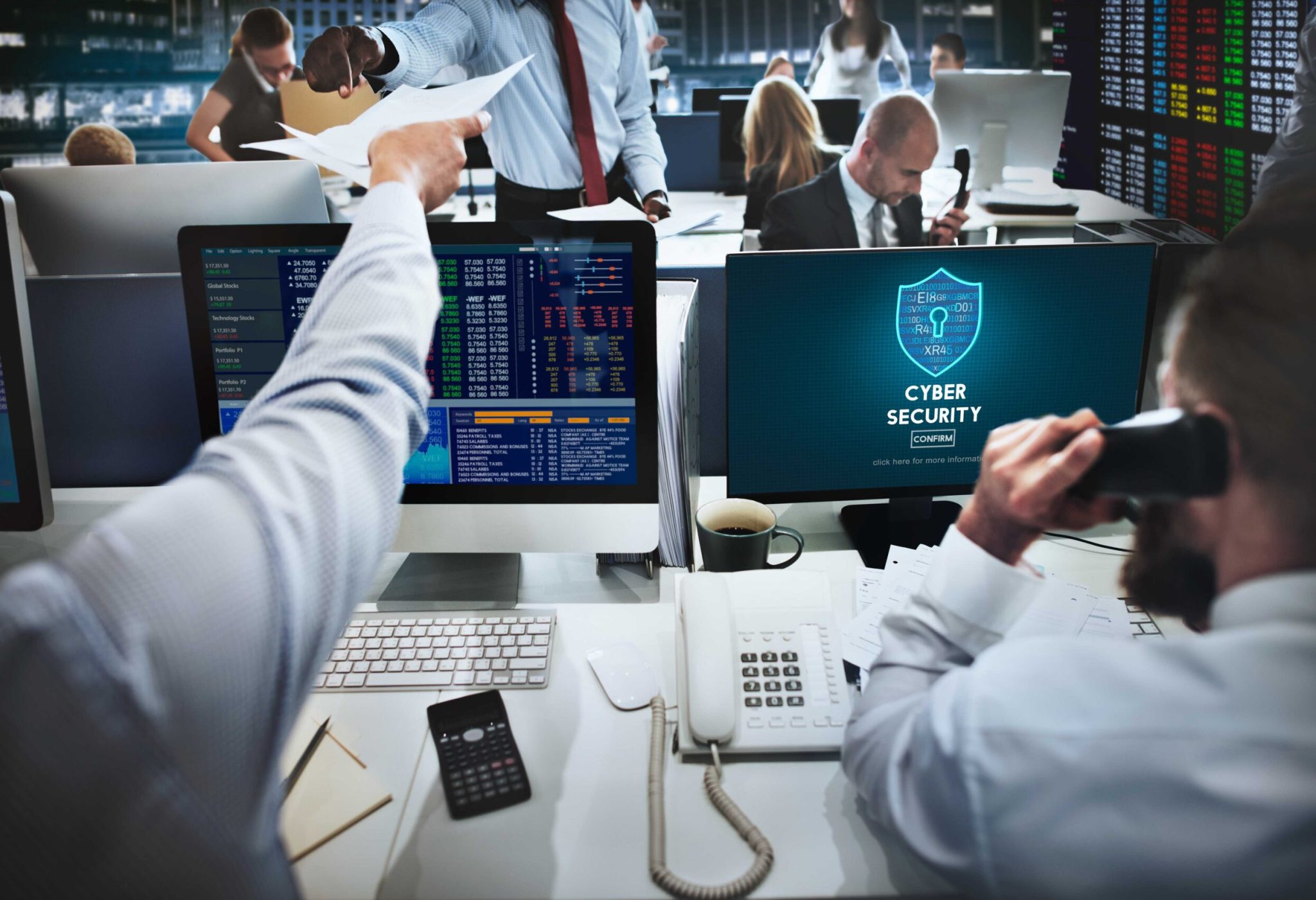 Group of professionals working at desks with computer screens in modern office setting